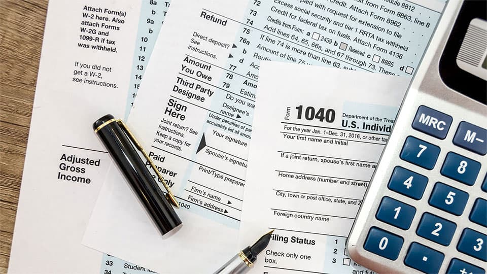 Tax forms and calculator sprawled out on table