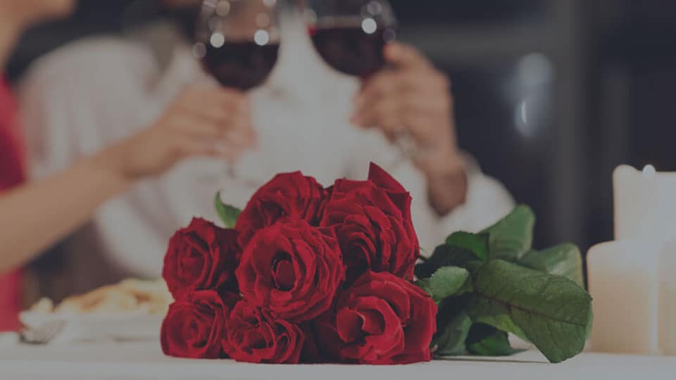 Romantic evening between two people with wine and rose and resting on table