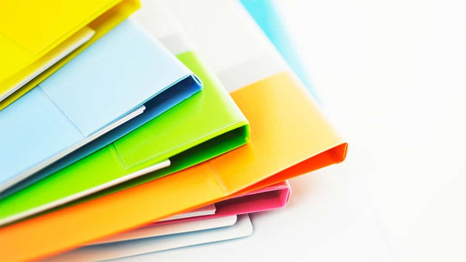 Various colored folder stacked on top of one another on flat surface