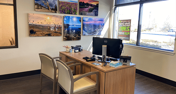 Office with computer and two chairs and large windows in the background