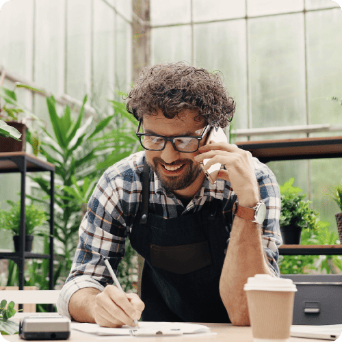 Plan shop owner on phone call and writing on paper at desk