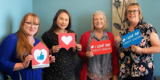 Four women standing together holding "# I Love My Credit Union" signs