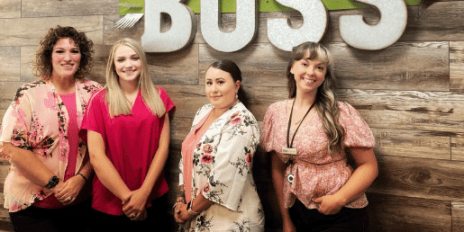 Group of women standing next to BOSS sign in credit union branch