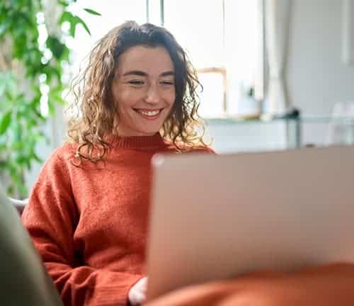 Mujer sonriente usando portátil en apartamento