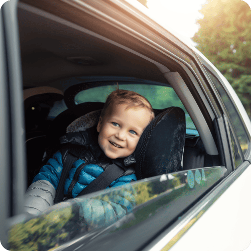 Happy little boy in backseat of car looking out the window