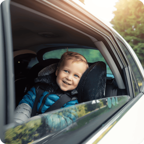 Niño feliz en el asiento trasero del coche mirando por la ventanilla