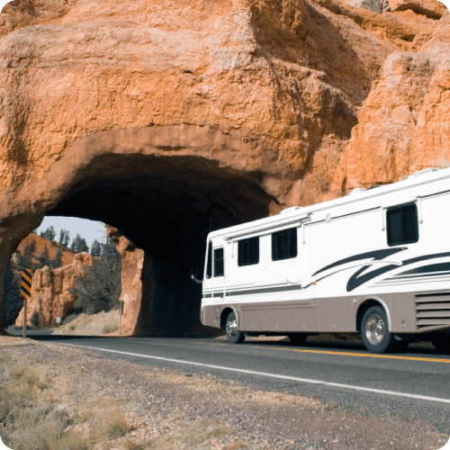 Autocaravana viajando bajo un puente formado por roca roja