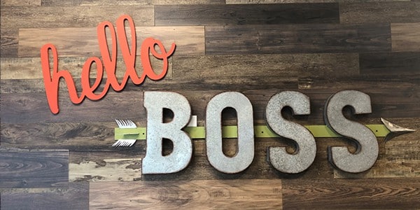 "Hello Boss" sign hanging on wood paneled wall