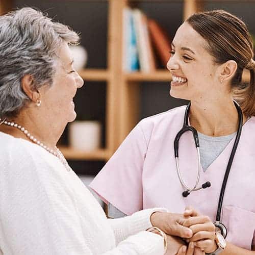 Doctora sonriendo y dándole la mano a una paciente