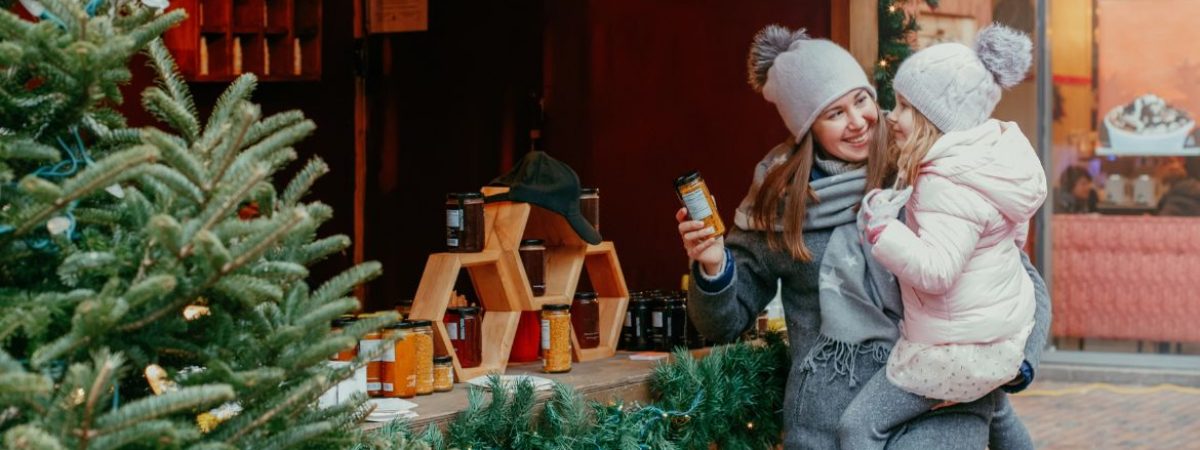 Woman holding a child in front of a store at Christmastime