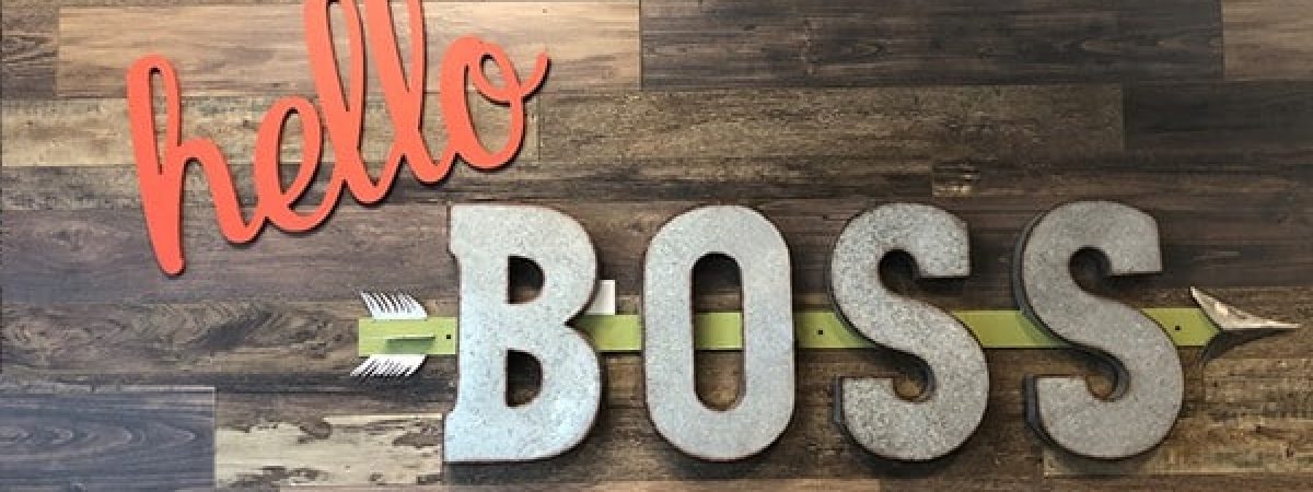 "Hello Boss" sign hanging on wood paneled wall